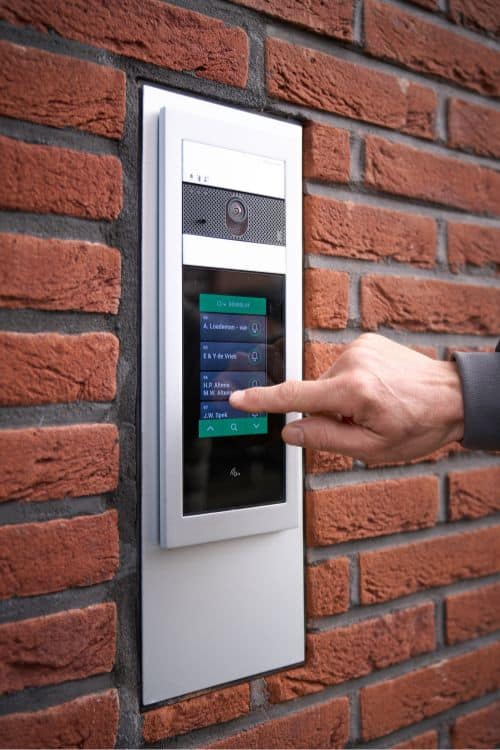 Close-up van een modern Comelit deurstation met camera en interactief touch beeldscherm, benadrukt de componenten van het intercomsysteem.