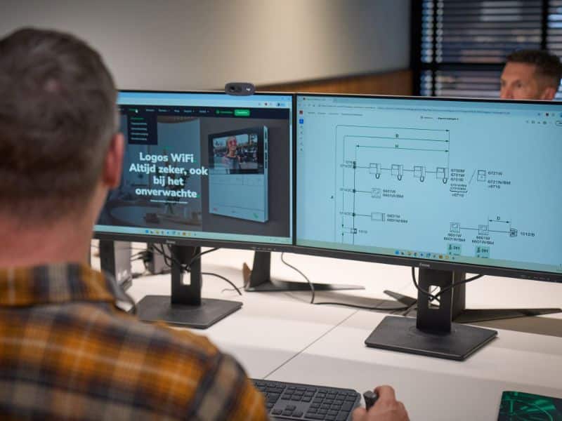 Technisch specialist van Intercom Partners zit achter bureau en werkt geconcentreerd aan bouwtekeningen en installatieschema's.