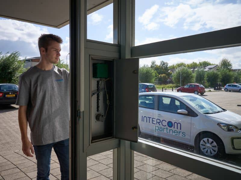 Monteur van Intercom Partners monteert en werkt een nieuw entreepaneel bij een appartementencomplex netjes af.